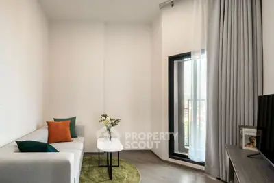 Modern living room with cozy sofa, stylish decor, and large window for natural light.