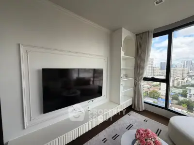 Modern living room with large TV and city view from window, featuring elegant built-in shelving.