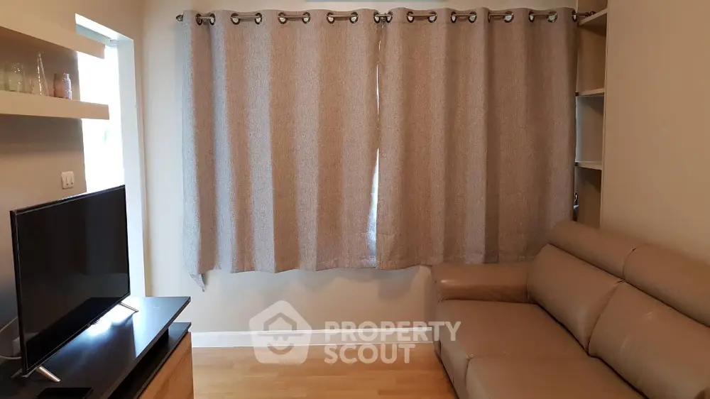 Cozy living room with modern sofa and flat-screen TV, perfect for relaxation.