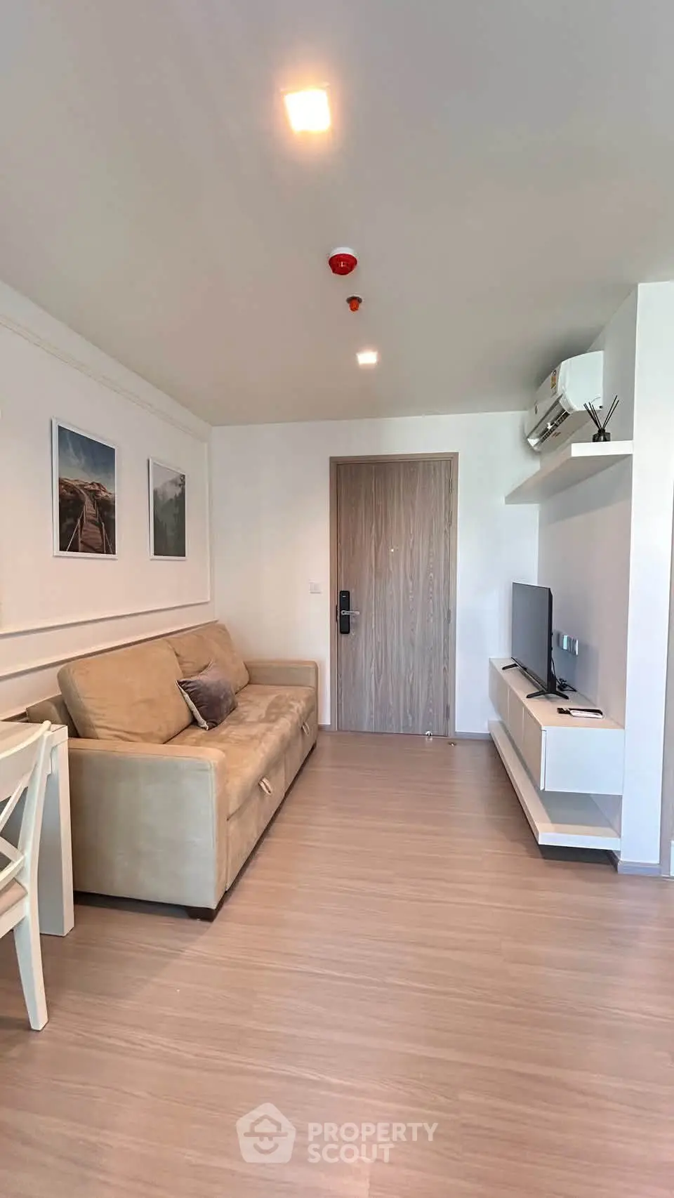 Modern living room with beige sofa, wall-mounted TV, and stylish decor in a cozy apartment.