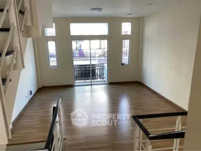 Spacious living room with wooden flooring and balcony access in modern apartment.