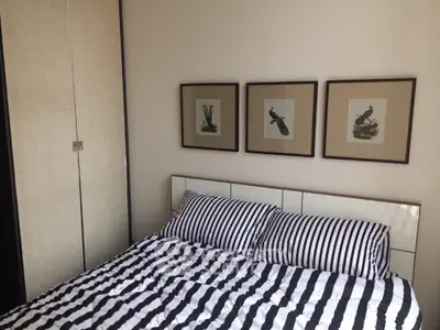 Cozy bedroom with striped bedding and elegant framed bird artwork, perfect for relaxation.