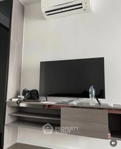 Modern living room with sleek TV setup and air conditioning unit.