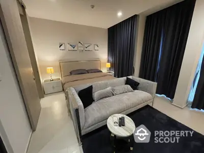 Luxurious bedroom with plush king-sized bed, elegant sofa, and chic decor, featuring ambient lighting and modern furnishings for a serene living experience.