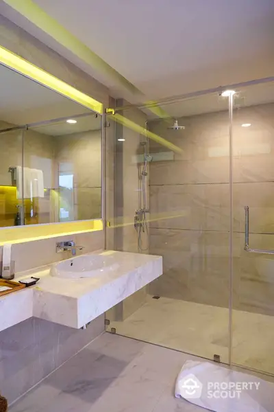 Luxurious modern bathroom with glass shower and marble sink in elegant home.