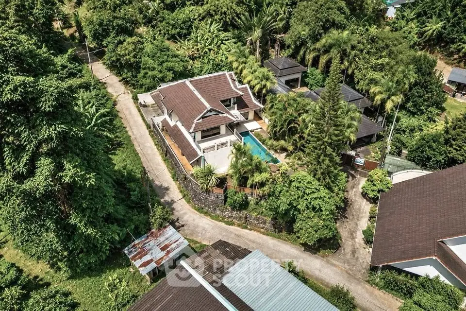 Stunning aerial view of a luxurious villa with private pool surrounded by lush greenery, perfect for serene living.