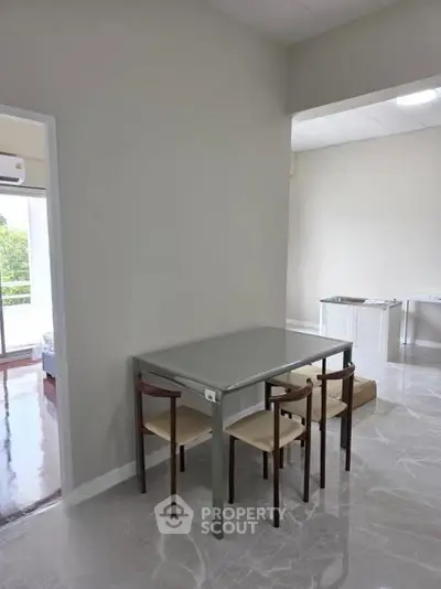 Modern dining area with sleek table and chairs in a bright, open-plan apartment.