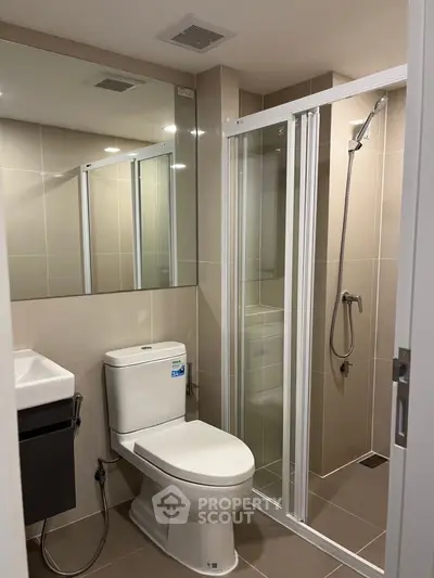 Modern bathroom with glass shower and sleek fixtures in contemporary apartment.