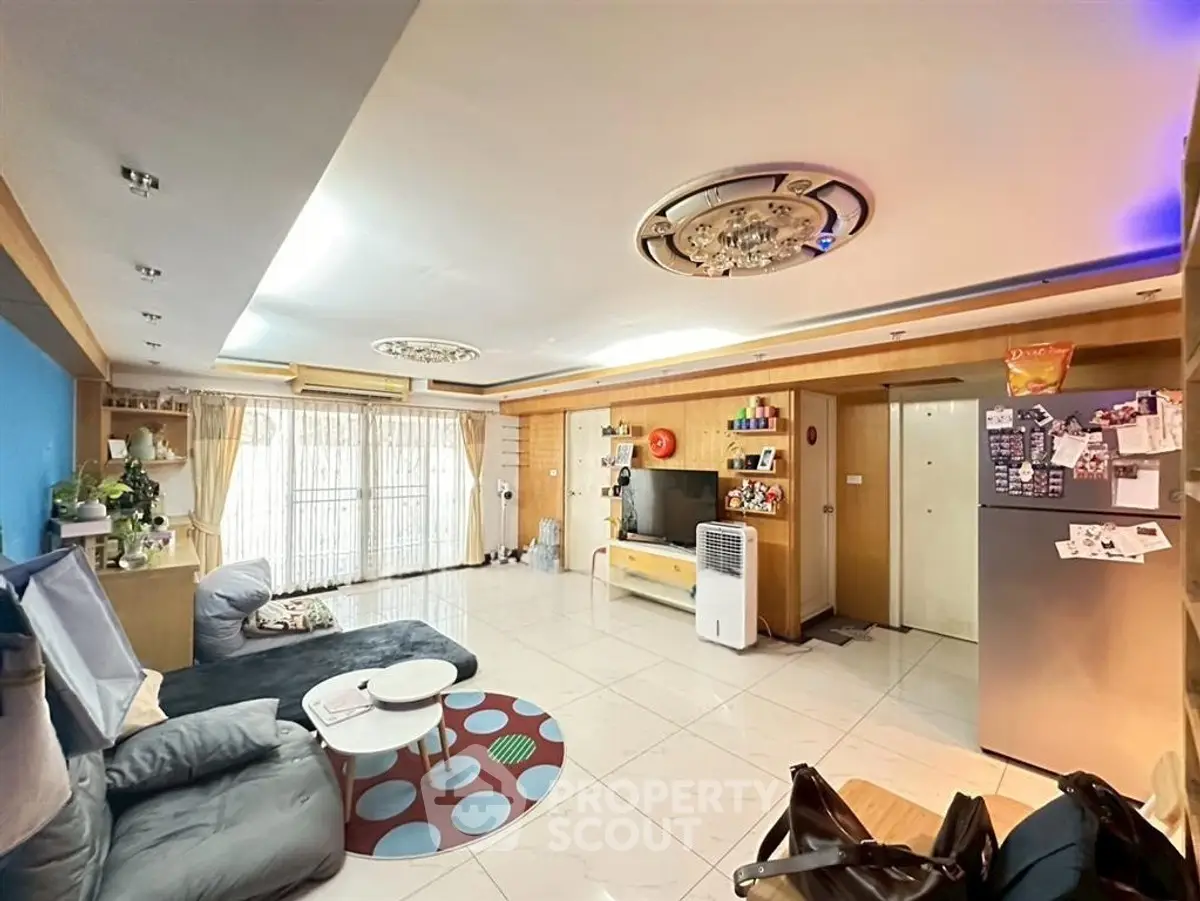 Spacious living room with modern decor and natural light, featuring a cozy seating area and stylish ceiling design.