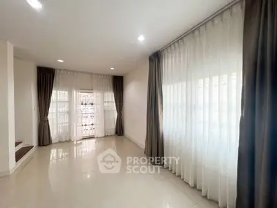 Spacious living room with large windows and elegant curtains