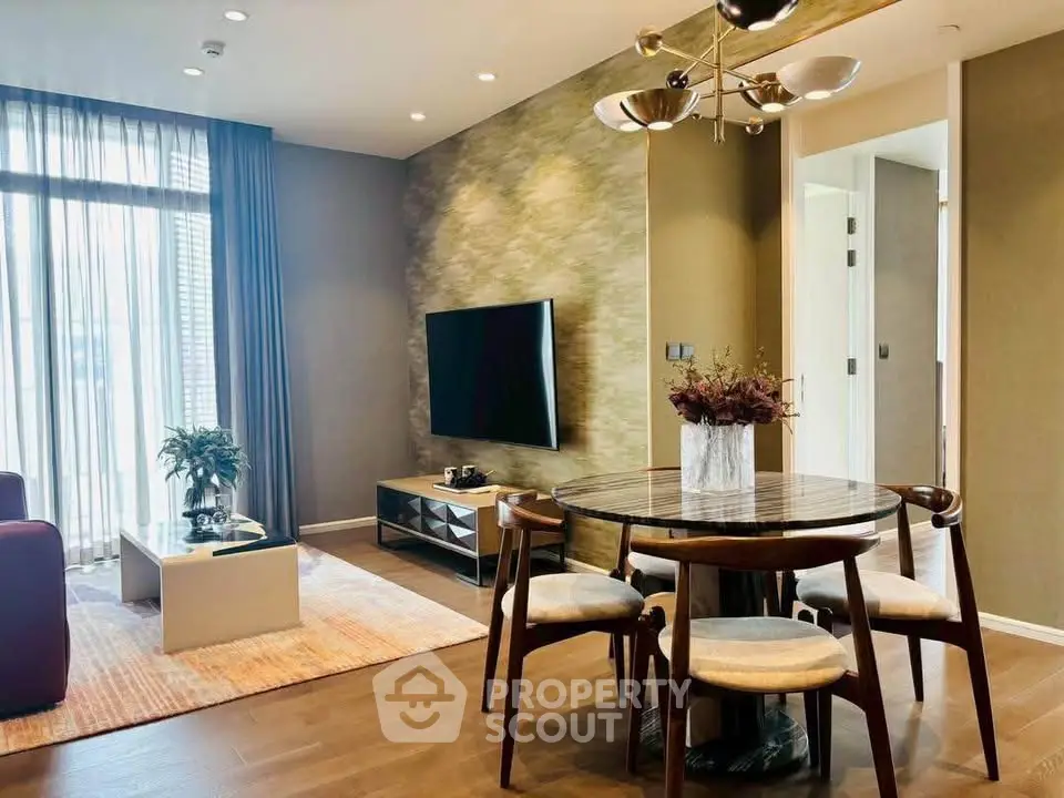 Modern living room with stylish furniture and large TV, featuring elegant lighting and floor-to-ceiling windows.