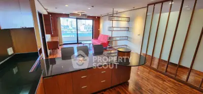 Spacious modern living room with open kitchen and city view balcony, featuring sleek wooden flooring and stylish design.