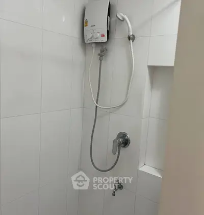 Modern bathroom shower with water heater in sleek white tile setting.