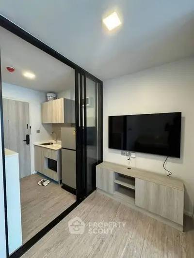 Modern compact living room with open kitchen and sleek TV setup