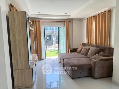 Spacious living room with plush sofa and garden view, perfect for relaxation.