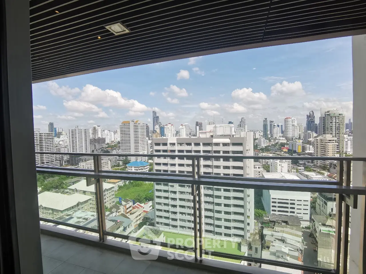 Stunning high-rise balcony view of city skyline with modern architecture and clear blue sky.