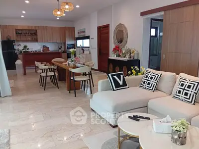Spacious open-layout living room with modern kitchen and elegant decor, perfect for family gatherings.