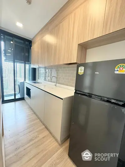 Modern kitchen with sleek cabinetry and stainless steel fridge in a bright apartment.