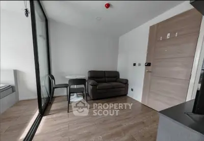 Modern living room with sleek furniture and wooden flooring in a compact apartment.