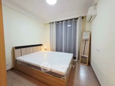 Modern bedroom with wooden flooring, large window, and air conditioning unit.