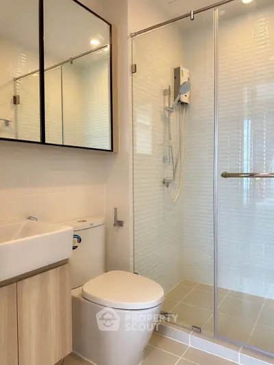 Modern bathroom with glass shower and sleek fixtures in contemporary apartment.