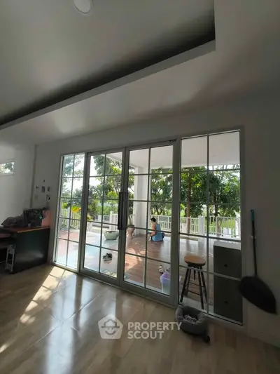 Spacious living room with large glass doors opening to a lush garden view, perfect for relaxation.