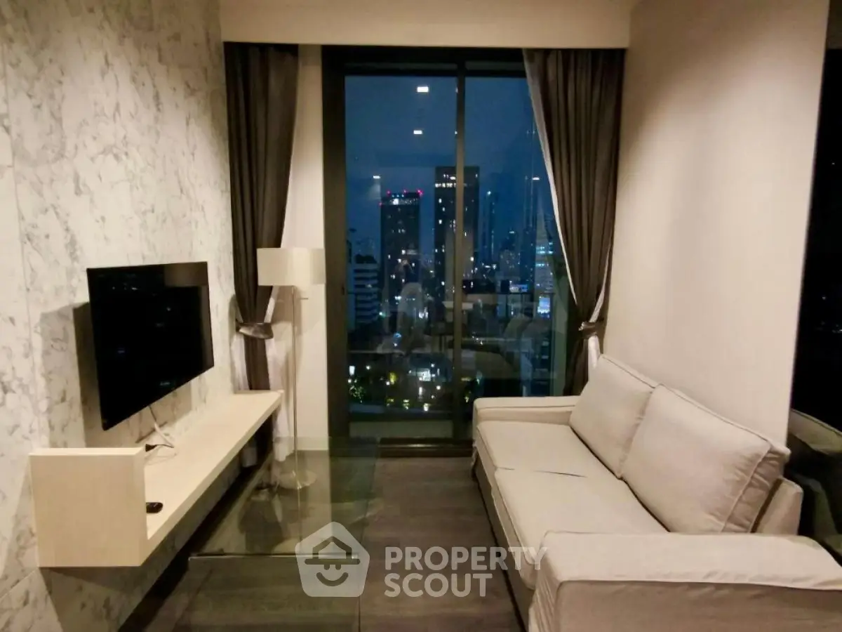 Modern living room with city view, featuring sleek furniture and floor-to-ceiling windows.