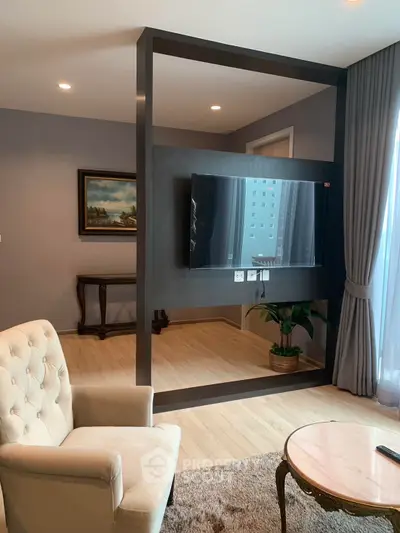 Modern living room with stylish decor and large TV, featuring elegant furniture and natural light.