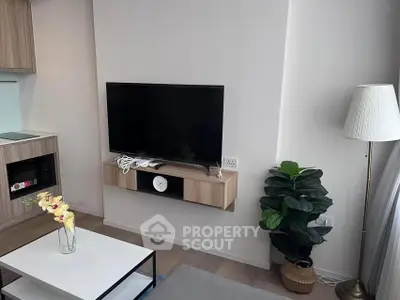 Modern living room with wall-mounted TV, stylish furniture, and indoor plant for a cozy ambiance.