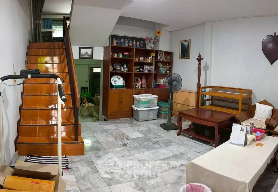 Cozy living room with wooden staircase and decorative shelves in a charming home.