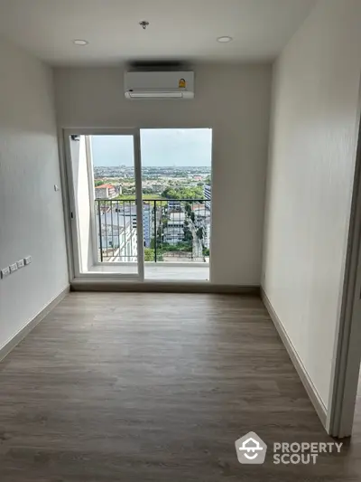 Spacious room with large window offering stunning city view and modern air conditioning unit.