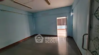 Spacious empty room with blue walls and open door leading to balcony