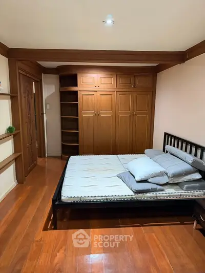 Spacious bedroom with wooden flooring and built-in wardrobe, perfect for cozy living.