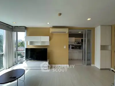 Modern living room with open layout and stylish furniture, featuring a large TV and air conditioning.