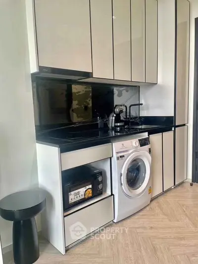 Modern kitchen with sleek cabinetry, built-in washing machine, and microwave, perfect for urban living.