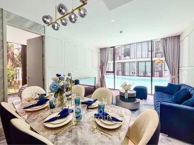 Luxurious dining and living area with pool view, elegant decor, and modern furnishings.
