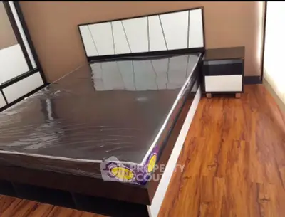 Modern bedroom with sleek bed frame and wooden flooring, perfect for a cozy retreat.