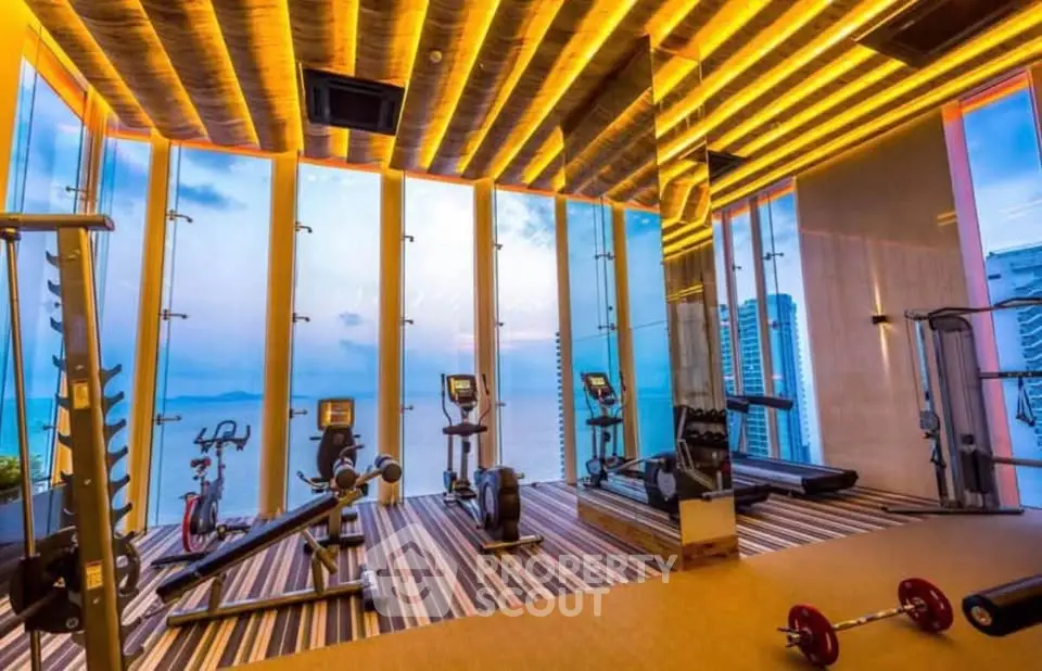 Luxurious high-rise gym with panoramic ocean views and modern fitness equipment.