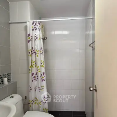 Modern bathroom with floral shower curtain and sleek tile design.