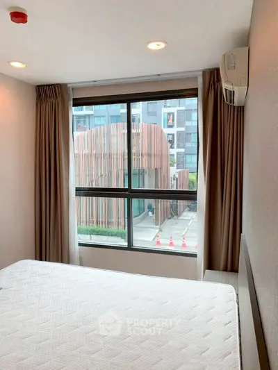 Modern bedroom with large window and urban view, featuring air conditioning and contemporary design.