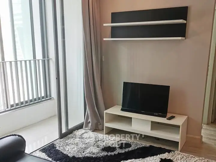 Modern living room with sleek TV stand and balcony access in a stylish apartment.