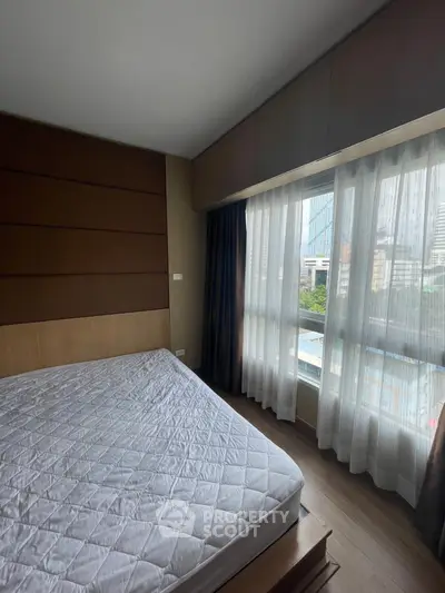 Spacious bedroom with large window offering city view, featuring modern design and ample natural light.