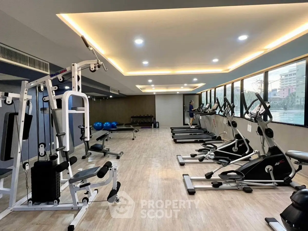 Modern gym with state-of-the-art equipment and large windows offering city views.