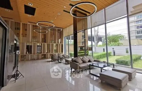 Spacious modern living room with high ceilings and large windows offering a garden view.