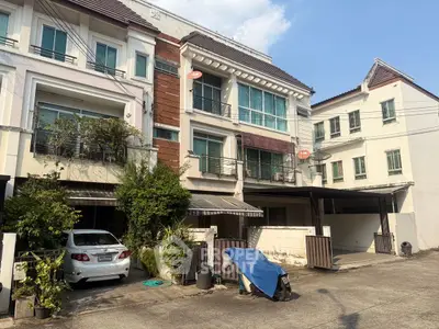 Spacious multi-story townhouse with carport and lush greenery in a serene neighborhood.