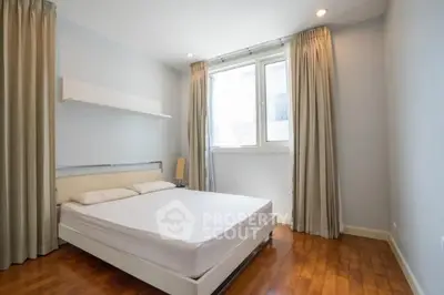 Spacious bedroom with wooden flooring and large window for natural light.