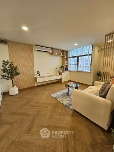 Spacious modern living room with stylish decor and large windows.