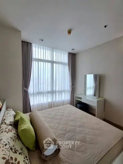 Spacious bedroom with large window and modern decor in a high-rise apartment.