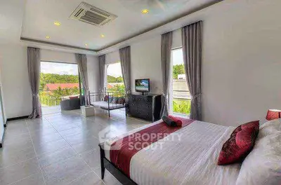 Spacious bedroom with large windows and scenic view, featuring modern decor and natural light.