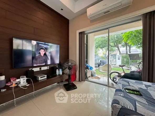 Modern living room with TV, air conditioning, and sliding glass doors to garden.
